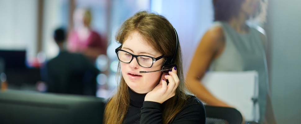 Female professional with Down syndrome speaking into a mic in the office.