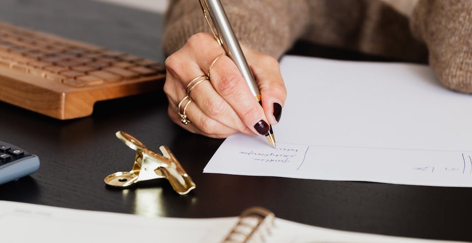 business lady taking notes while sitting at desk.