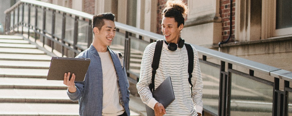 two young adult Asian males talking and smiling, while walking down the stairs