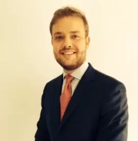 Man in a suit with a red tie smiling at the camera.