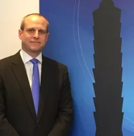 Man in a suit standing beside silhouette of a tall building.