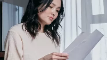 Woman sitting and reading a document by a window