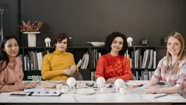 Four people sitting at a conference table with bookshelves in the background.