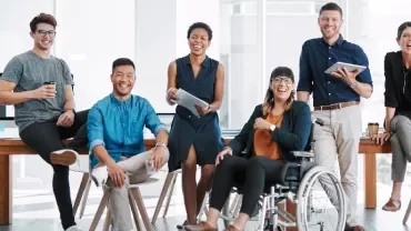 A diverse group of colleagues smiling in a modern office setting.