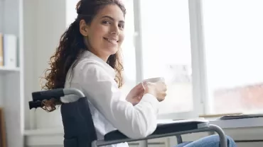 Woman in wheelchair smiling with a cup