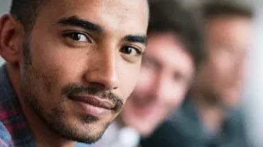 Portrait of a man in focus with two others blurred in the background.