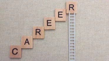 Scrabble tiles spelling 'CAREER' arranged like stairs next to a ladder.