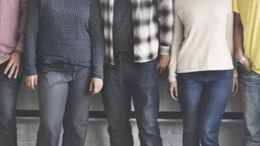 Four people standing side by side with casual clothing.