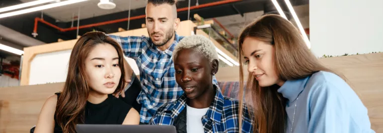 Four working professionals of different race and gender looking at computer screen