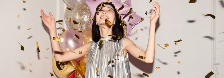 asian woman celebrating hands in the air, confetti