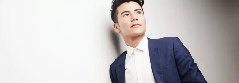 Man in a blue suit and white shirt looking off into distance.