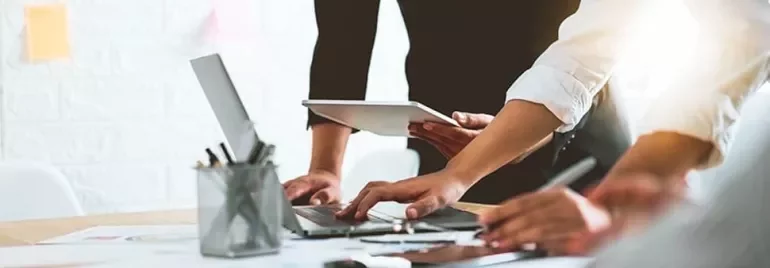 People collaborating with laptops and tablets around a table.