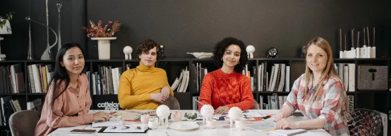 Four people sitting at a conference table with bookshelves in the background.