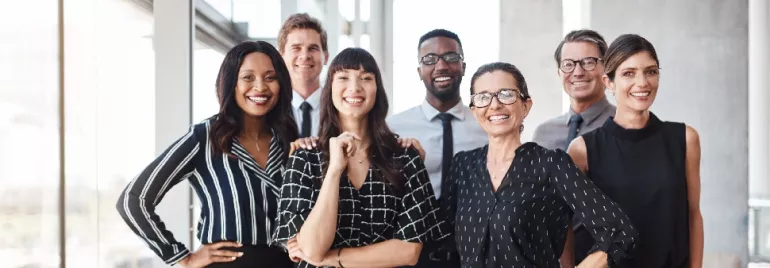 A diverse group of professionals smiling in an office setting.
