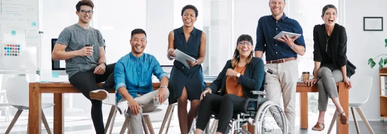 A diverse group of colleagues smiling in a modern office setting.