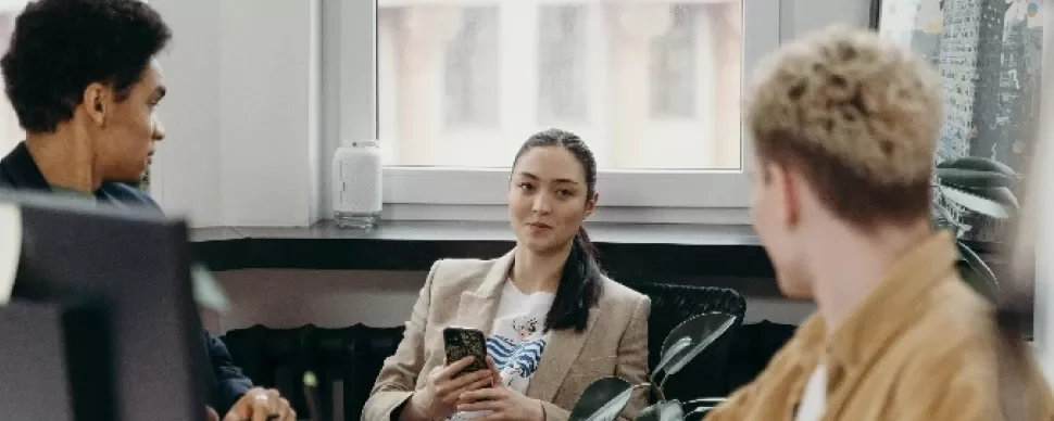 Three colleagues having a discussion in a modern office.