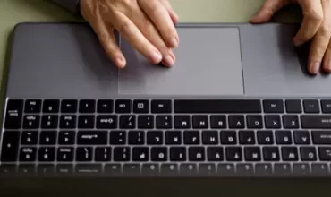 Individual engaged in typing on a laptop, with fingers on the keyboard.
