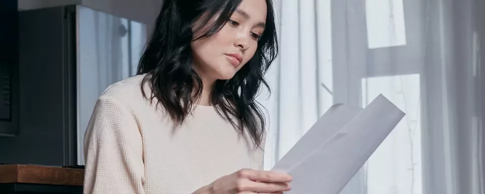 Woman sitting and reading a document by a window