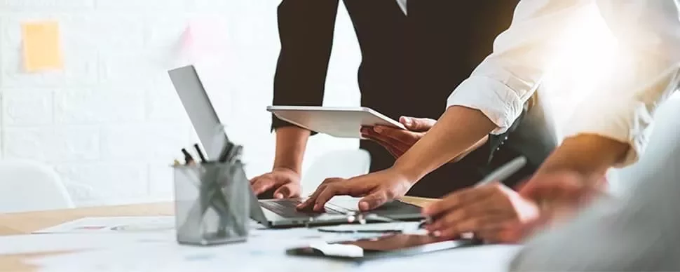 People collaborating with laptops and tablets around a table.