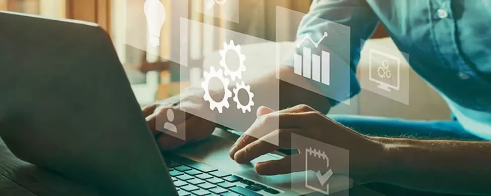 Hands typing on a laptop with overlay icons of gears and graphs.