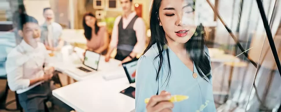 Woman writing on glass board during a meeting