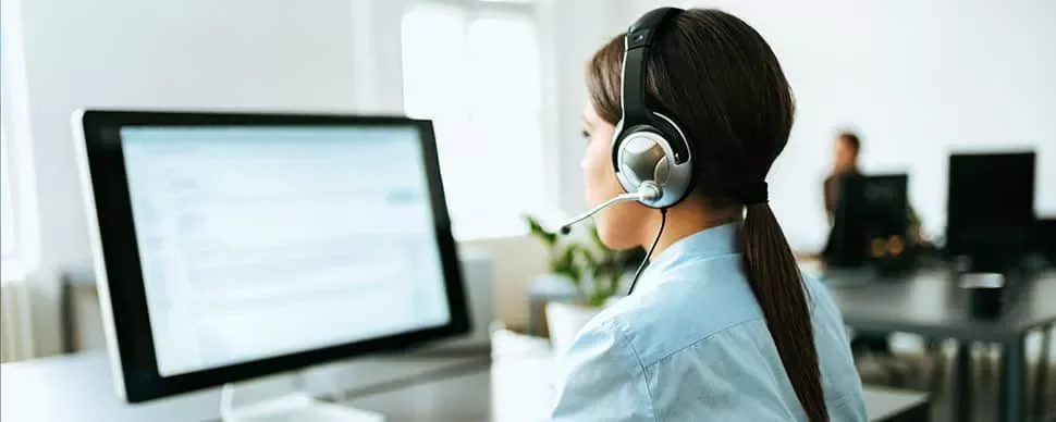 Person with a headset working at a desktop computer.