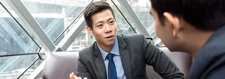 Two businessmen in discussion inside a modern office building.