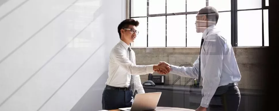 Two people shaking hands in a bright office