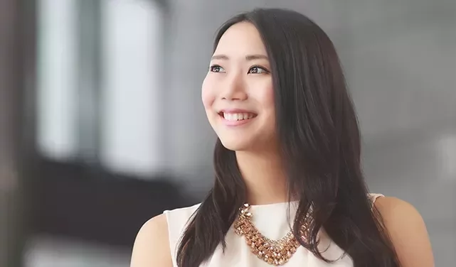 A woman with long hair smiling and looking to the side.