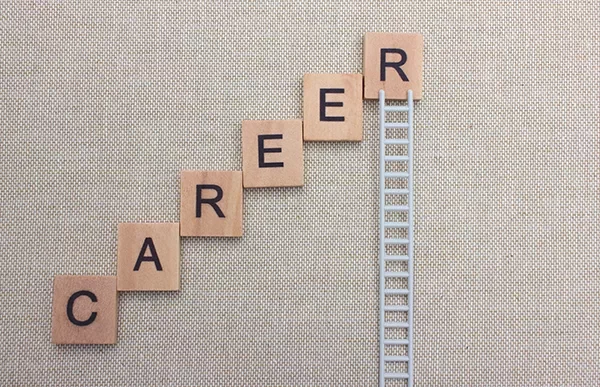 Scrabble tiles spelling 'CAREER' arranged like stairs next to a ladder.